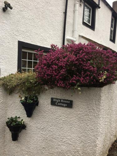 a building with purple flowers on the side of it at High House Cottage - A traditional home from home in St Bees