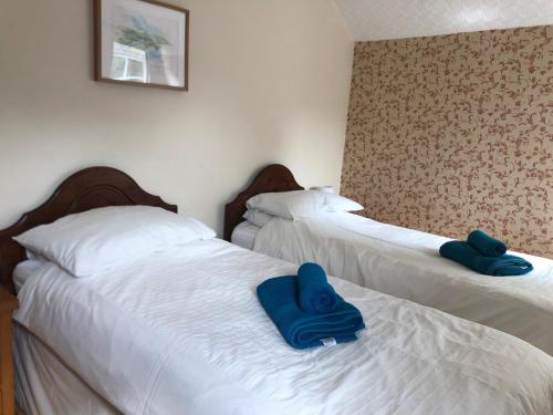 two beds in a room with blue towels on them at High House Cottage - A traditional home from home in St Bees