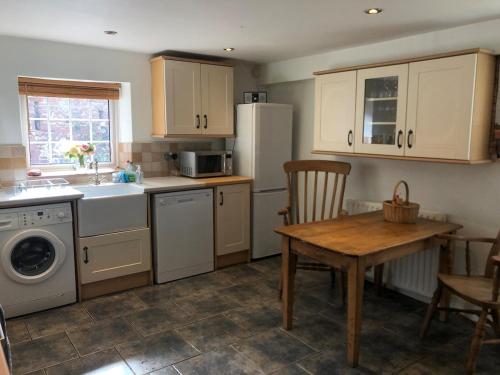 a kitchen with a table and a sink and a refrigerator at High House Cottage - A traditional home from home in St Bees