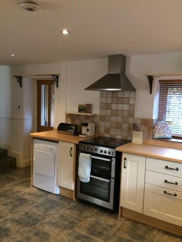a kitchen with white cabinets and a stove top oven at High House Cottage - A traditional home from home in St Bees