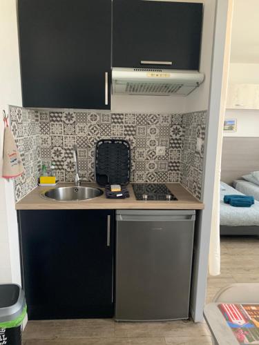 une petite cuisine avec un évier et une cuisinière dans l'établissement Charmant appartement cosy, à Rochefort