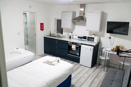a room with two beds and a kitchen with a sink at Centrally Located Apartments in Cardiff