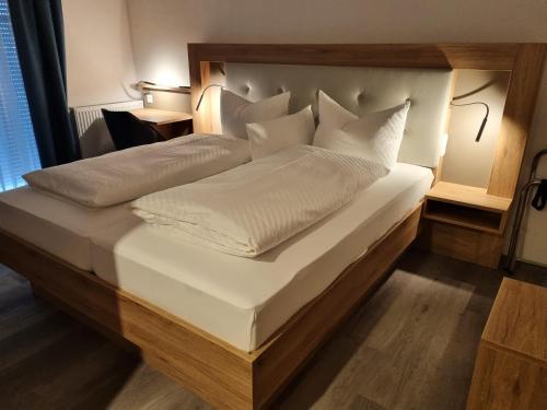 Elle comprend un grand lit avec des draps et des oreillers blancs. dans l'établissement Hotel Julia am Deich, à Norddeich
