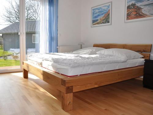 a wooden bed in a bedroom with a large window at Ferienwohnungen im Veenhuus - Tierfreundlich in Kellenhusen
