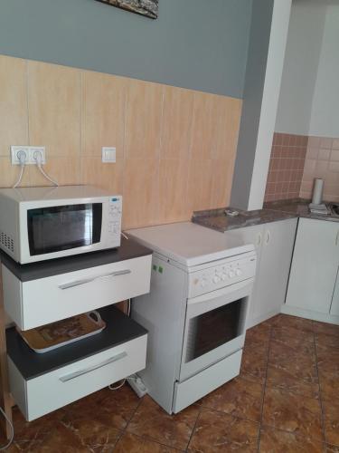 a kitchen with a microwave and a stove at Holiday Apartman in Bük