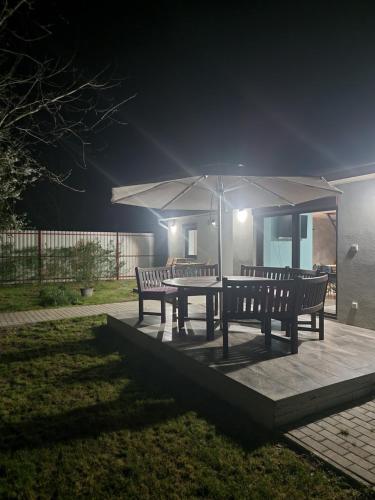 a patio with two benches and a table with an umbrella at Habitat of Dreams in Makó