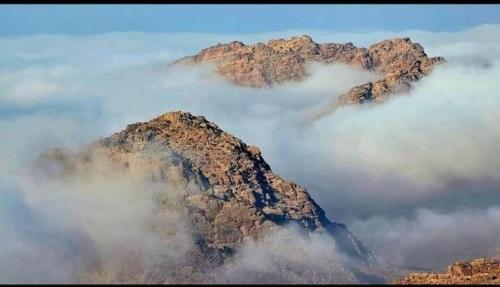 a mountain covered in fog with clouds on top of it at Dana Mount View the highest hotel in Jordan in Dana