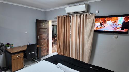 a bedroom with a bed and a tv on the wall at Bungalow Guest House Phase 4 in Gaborone