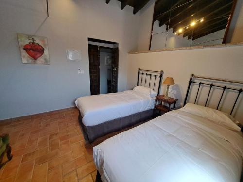 a bedroom with two beds and a table with a lamp at Hospedería Monasterio de San Leandro in Seville