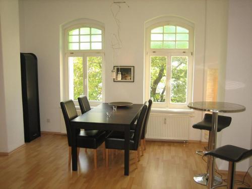 een eetkamer met een tafel en stoelen en 2 ramen bij Wölfele Apartment in Quedlinburg