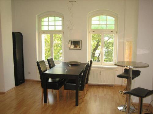 ein Esszimmer mit einem Tisch und Stühlen sowie 2 Fenstern in der Unterkunft Wölfele Apartment in Quedlinburg