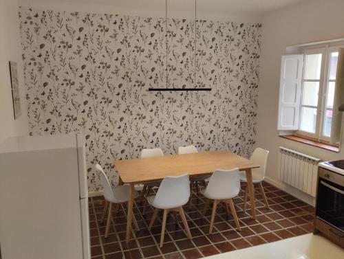 a kitchen with a wooden table and white chairs at Amplio piso en casa histórica en primera planta in Sabiñánigo