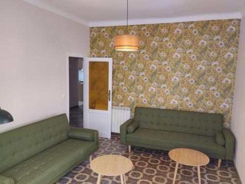 a living room with two green couches and two tables at Amplio piso en casa histórica en primera planta in Sabiñánigo
