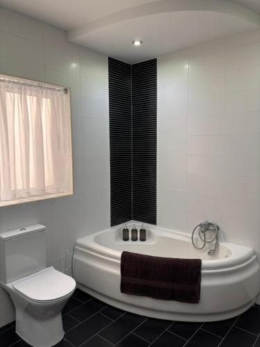 a white bathroom with a tub and a toilet at Family Apartment 1 in Bubaqra