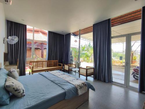 a bedroom with a large bed and large windows at Moc's Homestay-Phan Thiết in Ấp Tân Bình (2)