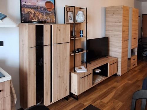 Una sala de estar con un gran mueble de madera con un televisor. en Студио Бяла, en Byala