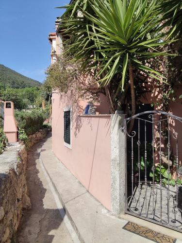 a pink building with a gate and a palm tree at Bougainvillea--Apartment By The Sea in Ston