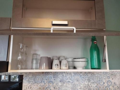 una mensola della cucina con piatti e una bottiglia verde di Appartement moderne a Le Puy en Velay