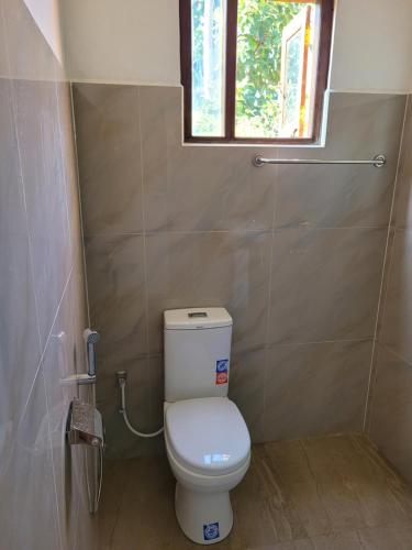 a small bathroom with a toilet and a window at Pearl House Homestay Dickwella in Dickwella