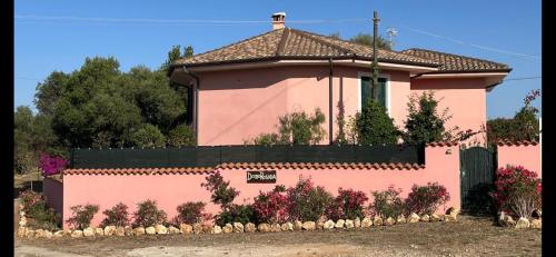 a pink house with a fence and flowers at Domo Rosada in Ottava Sassari