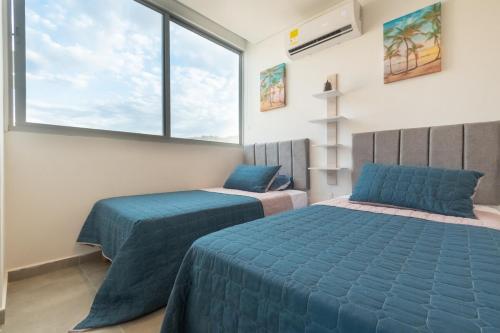 a bedroom with two beds and a large window at Rodadero Exclusivo - Pasos de Playa Salguero in Puerto de Gaira