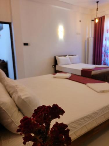 a bedroom with two beds and a vase of flowers at Pearl House Homestay Dickwella in Dickwella