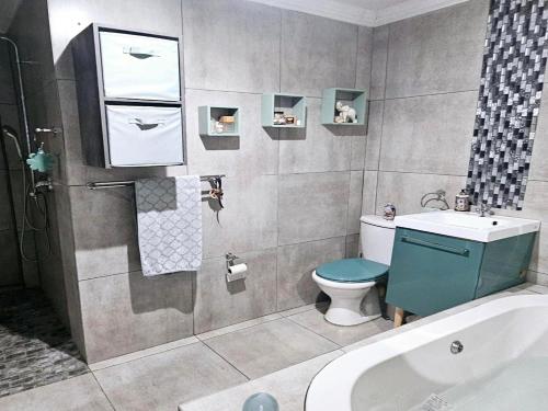 a bathroom with a toilet and a sink and a tub at Bosveld In Die Stad Lodge in Alberton