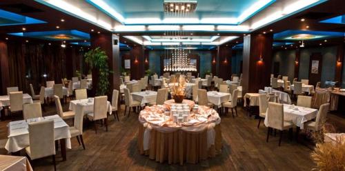 ein Esszimmer mit weißen Tischen und Stühlen sowie einem Kronleuchter in der Unterkunft Garden of Eden- Apartments Sweet Dreams Rey&Mar Saint Vlas in Sweti Wlas