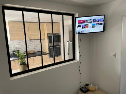 a flat screen tv hanging on a wall next to a window at Cozy vintage BNB house in Yerville
