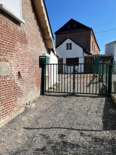 a gate in front of a brick building with a white house at Cozy vintage BNB house in Yerville