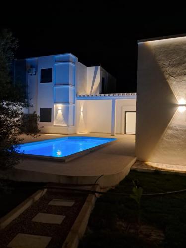 a swimming pool in front of a house at night at Villa Djerba hood in Banī Dinhet