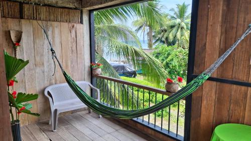 a hammock on the porch of a house at Posada Nore, Nuquí in Arusí