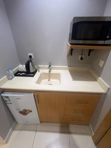 a kitchen with a sink and a microwave at فندق أجنحة سمو - smo suites hotel in Riyadh