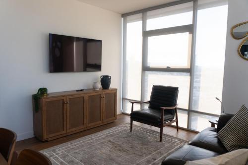 a living room with a tv and a chair at Lux Condo San Ysidro Border in Tijuana