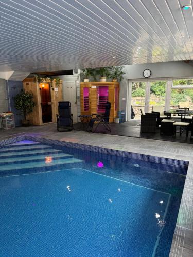 a swimming pool in a house with a table and a clock at Oakley Bed & Breakfast - Vegetarian, Vegan in Newcastle Emlyn