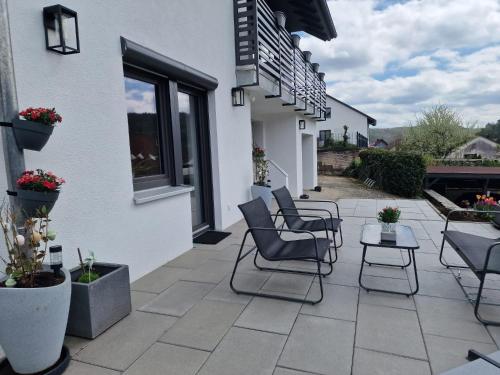 a patio with chairs and tables next to a building at FeWo mit großer Terrasse im Herzen der fränkischen Schweiz in Unterleinleiter