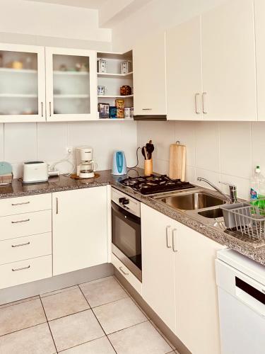 a white kitchen with white cabinets and a sink at Vista Dourada in Porto Santo