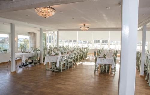 un salón de banquetes con mesas y sillas blancas y ventanas en Rågårdsvik, en Grundsund