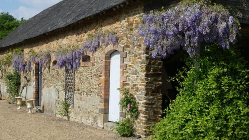 a brick building with purple wisteria on it at La Petite Lande in Ménil