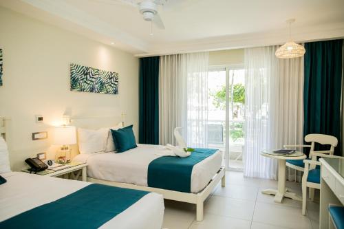 a hotel room with two beds and a table at Vista Sol Punta Cana Beach Resort & Spa - All Inclusive in Punta Cana