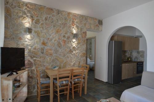 a living room with a table and a stone wall at Kathara Bay Apartments in Faliraki