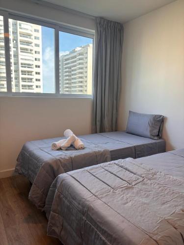two beds with a stuffed animal sitting on top of them at Suite na Barra - Rio Centro - Parque Olímpico in Rio de Janeiro