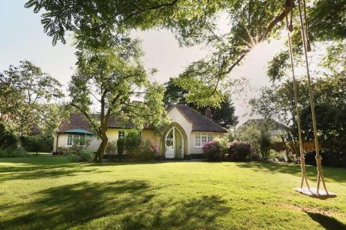 a house with a yard with a swing at Plantagenet, A Historic Country Cottage with Pool and Hot Tub in Boughton Aulph