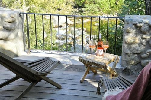 a table with two glasses of wine on a deck at Hotel Restaurant & Spa E Caselle in Venaco