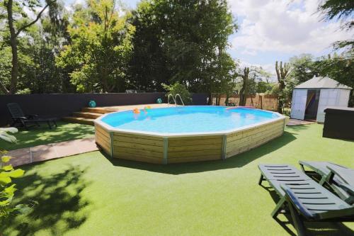a large pool in a yard with chairs and a table at Plantagenet, A Historic Country Cottage with Pool and Hot Tub in Boughton Aulph