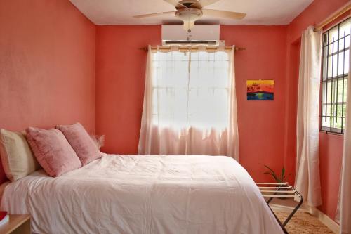 a bedroom with orange walls and a white bed at Cozy 1- Bed Apt Near Rodney Bay in Gros Islet