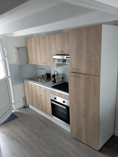 une cuisine avec des armoires en bois et un four à plaques de cuisson dans l'établissement Votre cocon à 1km de la plage, à Camiers