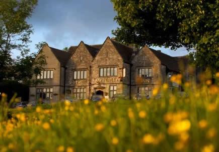 a large brick building in a field of flowers at Amberley Inn in Stroud