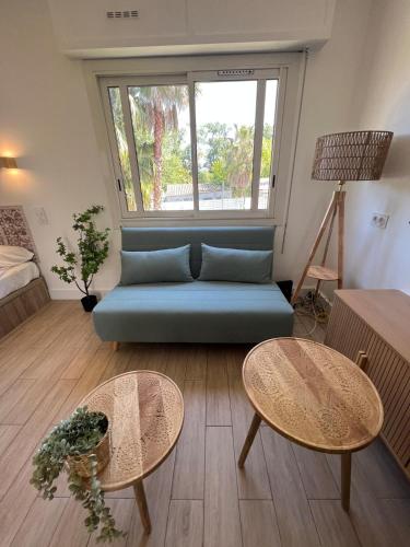 un salon avec un canapé bleu et deux tables dans l'établissement Seaside Studio with Terrace and Free Parking - Beach 2 Min Walk, à Villeneuve-Loubet