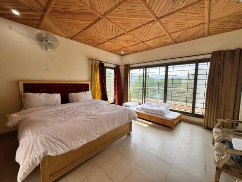 une chambre avec un grand lit et de grandes fenêtres dans l'établissement Haven Resort Bhurban, Murree, à Bhurban